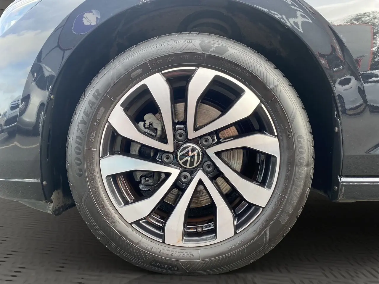 Gros plan sur la roue avant droite noire d'une Volkswagen Golf VIII 2022 avec jante alliage bicolore et pneu Goodyear.