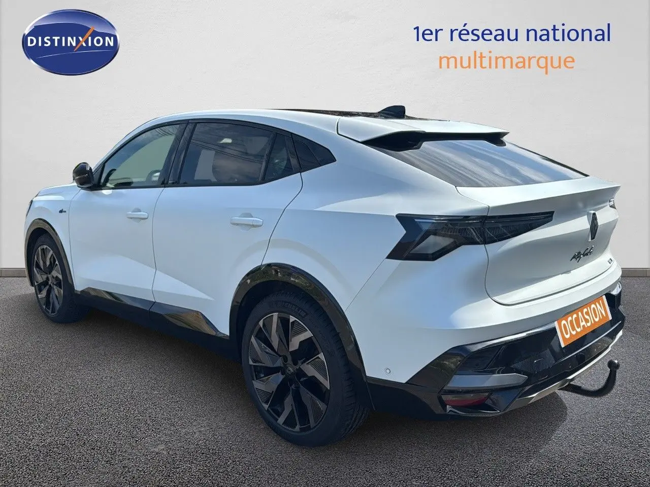 Vue 3/4 arrière droite d'une Renault Rafale 2024 blanc satin avec toit noir et attelage visible.