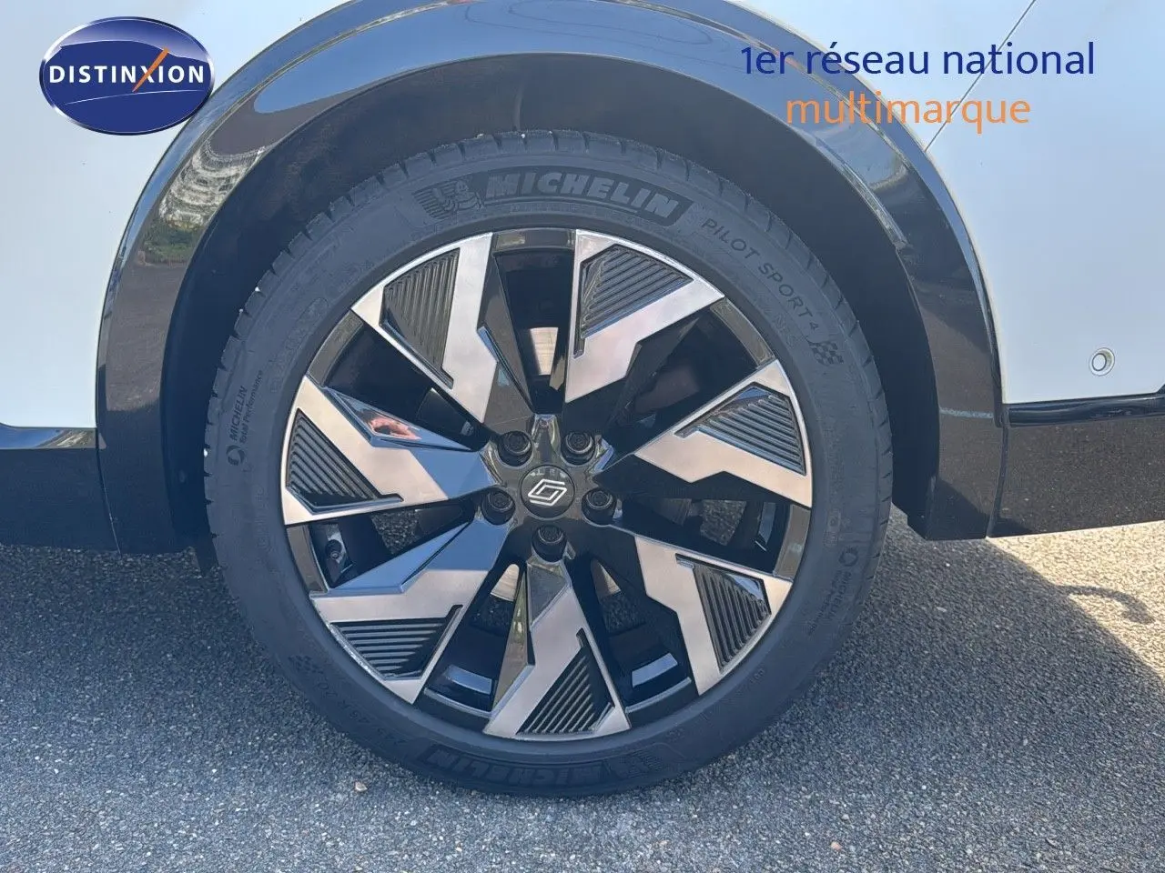 Gros plan sur la roue avant droite du Renault Rafale 2024 blanc satin avec jante alliage noire et argentée.