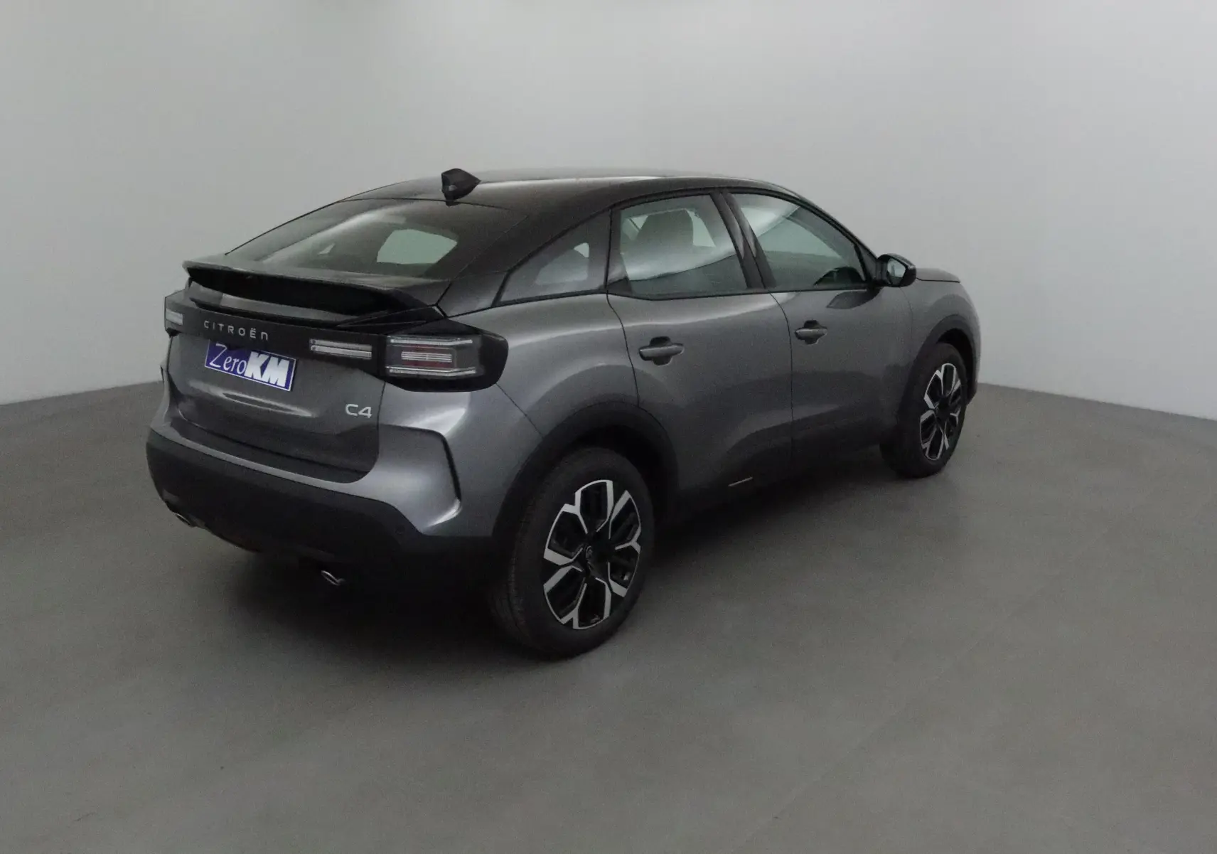Vue 3/4 arrière droite d'une Citroën C4 2025 gris Mercury et noir avec jantes alliage noires et toit noir.