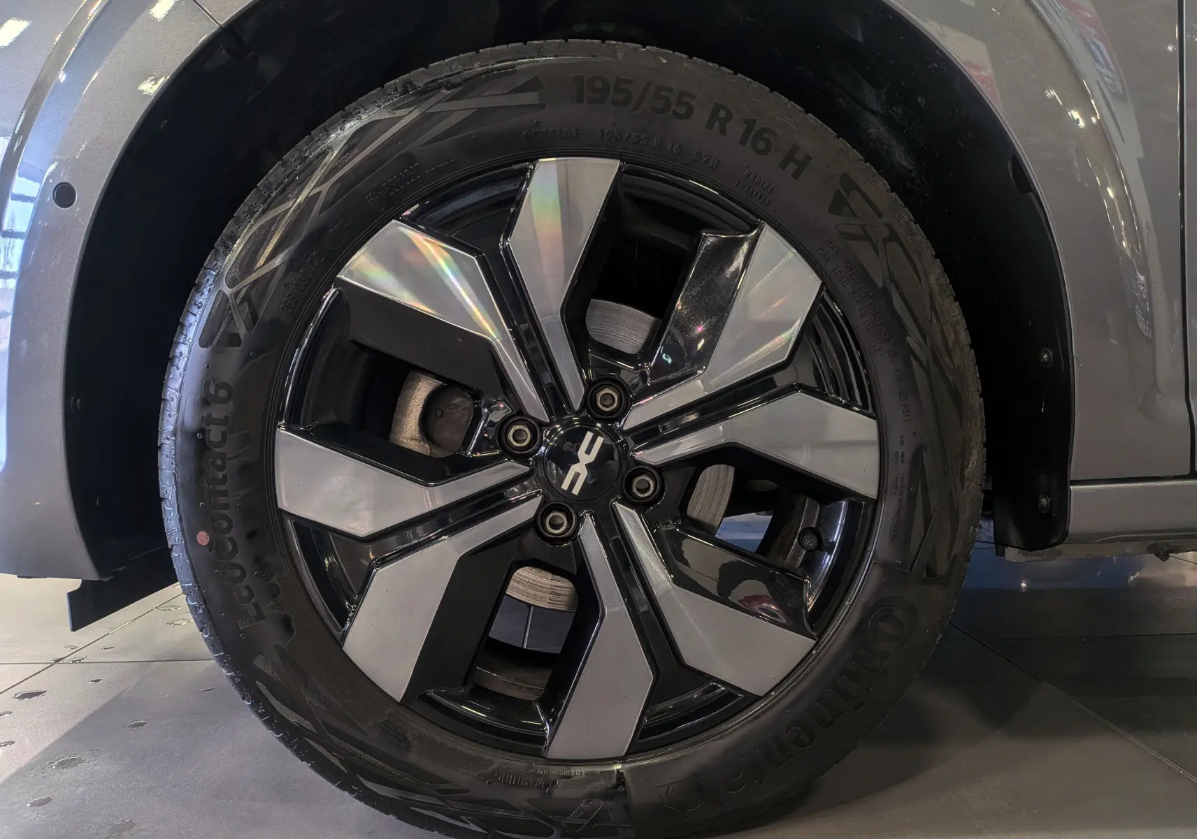 Gros plan sur la roue avant gauche d'une Dacia Sandero TCe 90 gris schiste avec jante alliage noire et argentée.