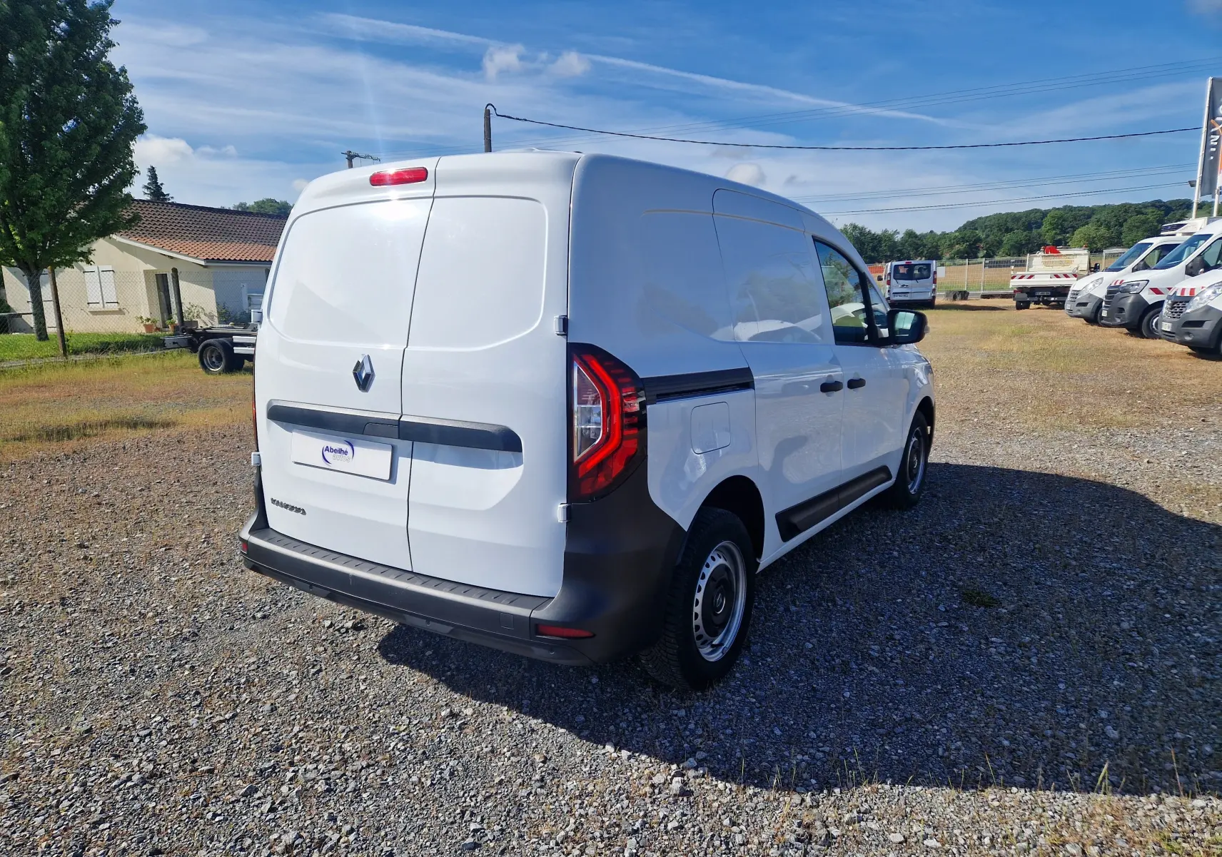 Vue 3/4 arrière droite d’un Renault Kangoo blanc 2023 utilitaire avec portes arrière battantes et feux arrière LED.