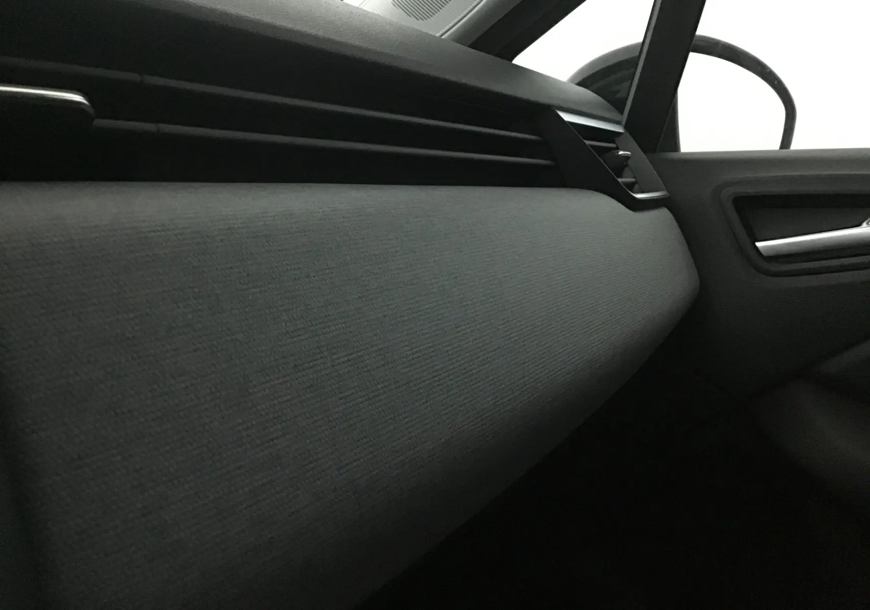 Vue rapprochée de la planche de bord côté passager de la Renault Clio V gris schiste avec aérateurs horizontaux noirs.