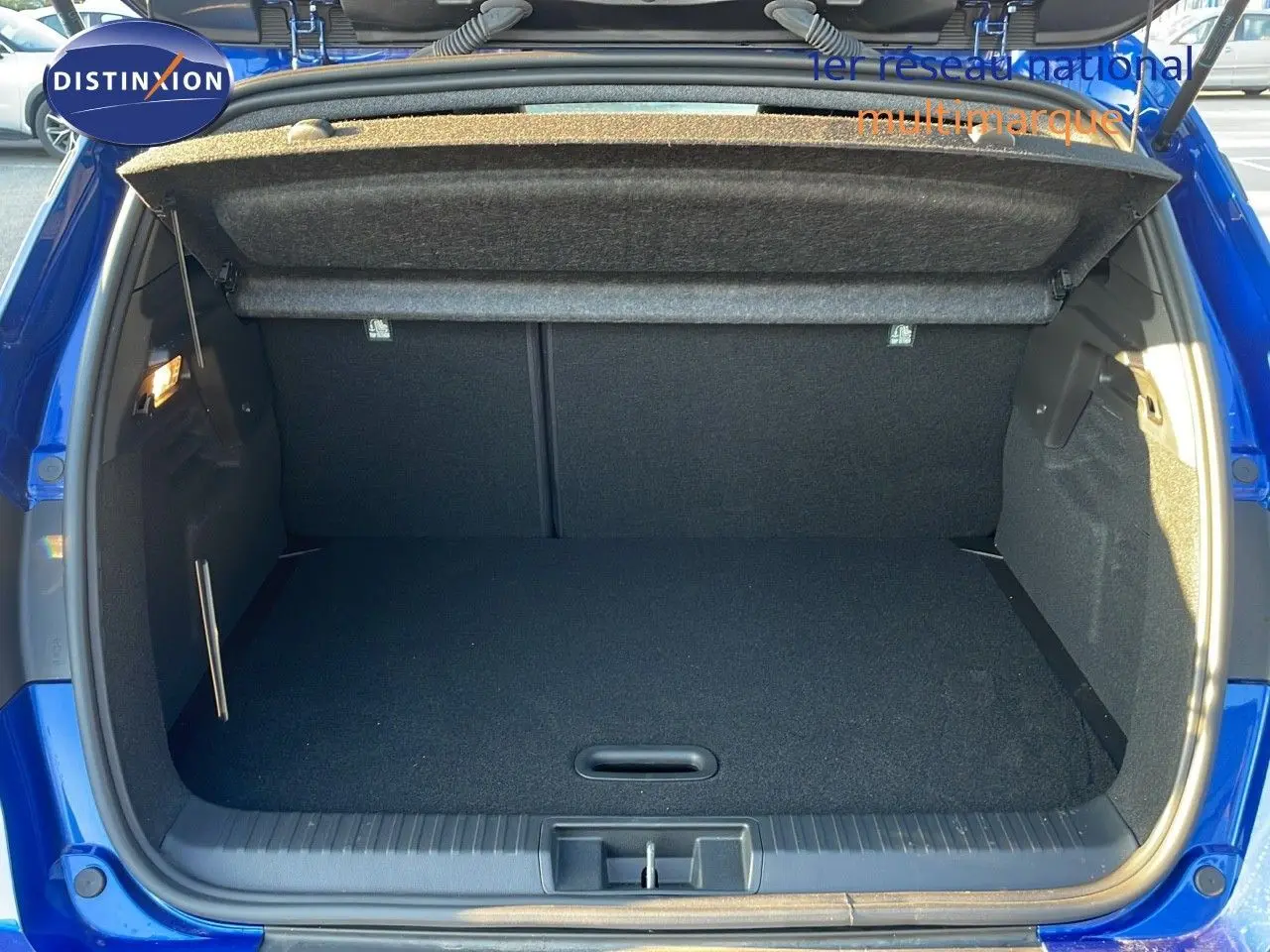 Coffre ouvert d'un Renault Captur E-Tech hybride 2025 bleu Iron Metal, montrant l'espace de chargement vide et la moquette noire.