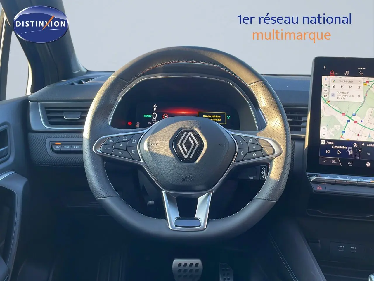 Vue rapprochée du volant en cuir noir du Renault Captur E-Tech Hybrid 2025 avec tableau de bord digital et écran tactile.