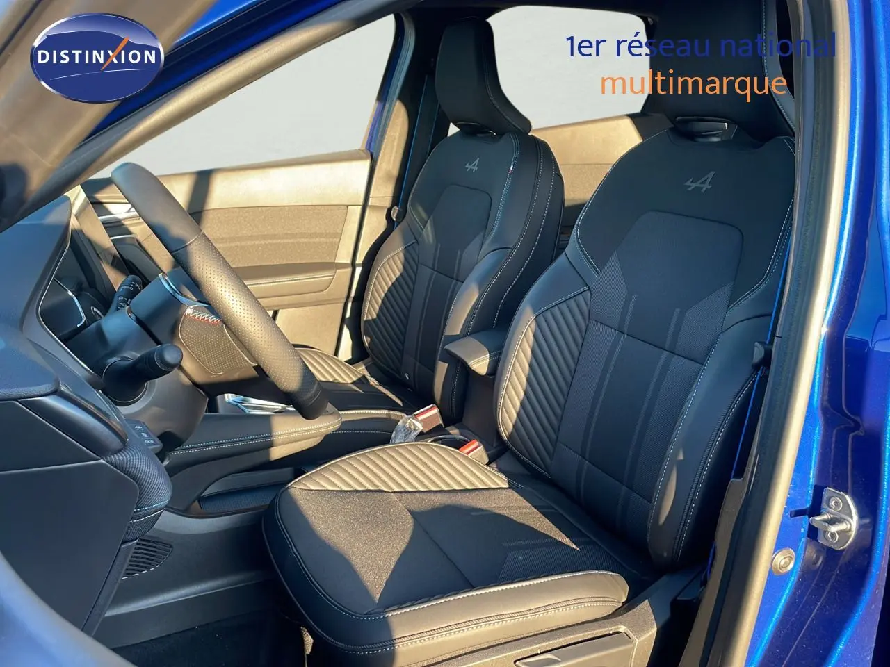 Intérieur avant du Renault Captur E-Tech hybride 2025 bleu Iron Metal, sièges noirs avec logo Alpine brodé.