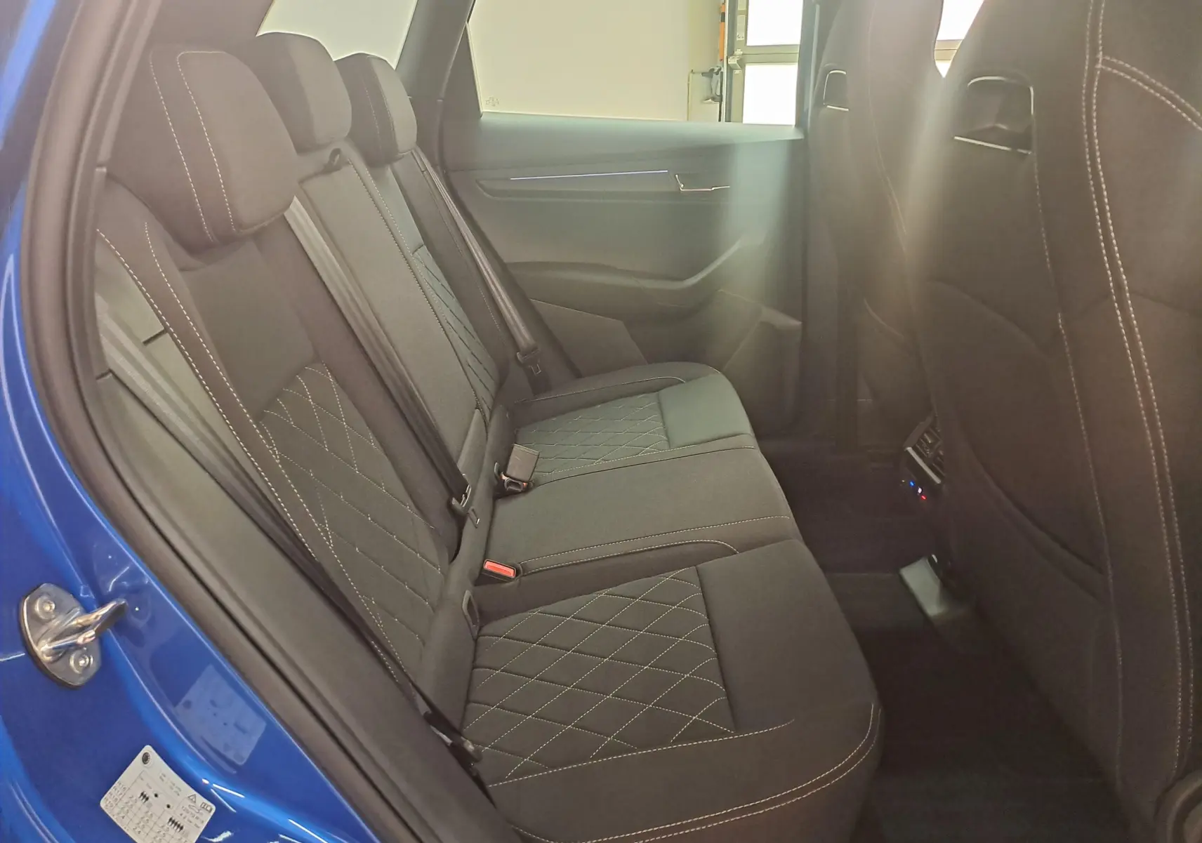 Vue intérieure côté gauche des sièges arrière en tissu noir avec surpiqûres contrastantes du Skoda Karoq Bleu RS 2025 Sportline.
