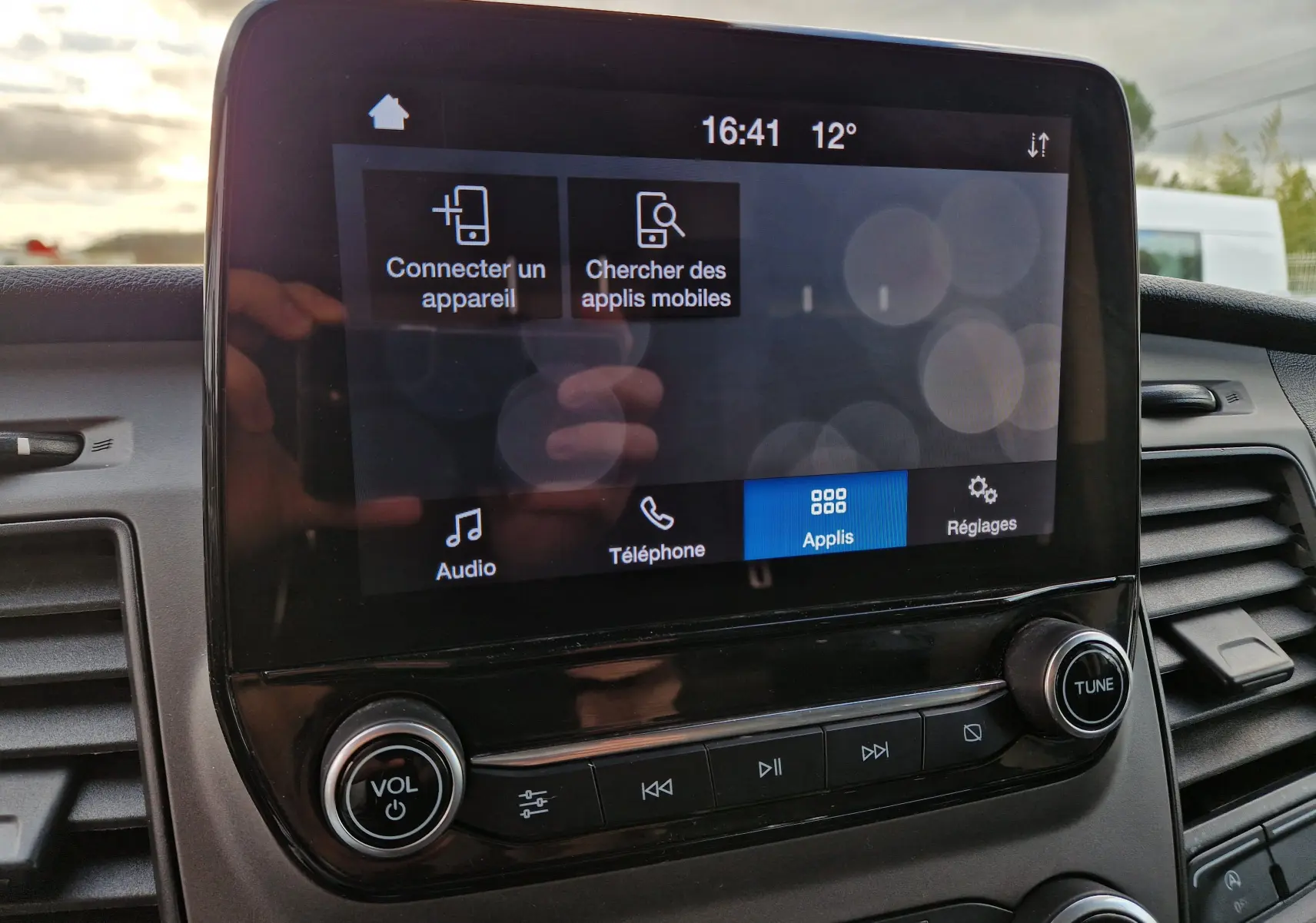 Écran tactile central du Ford Transit Custom blanc, affichant les options de connexion et applications, vue intérieure frontale.