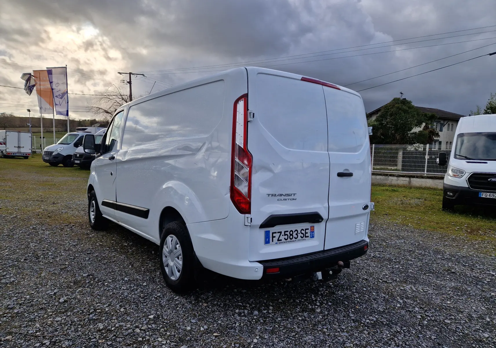 Vue arrière ouverte du fourgon blanc Ford Transit Custom L1H1 avec aménagements en bois sur les côtés du coffre.