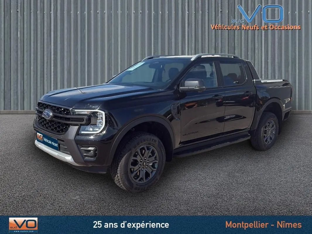 Ford Ranger Wildtrak noir en 3/4 avant droit, avec barres de toit, marchepieds et jantes alliage 18 pouces.