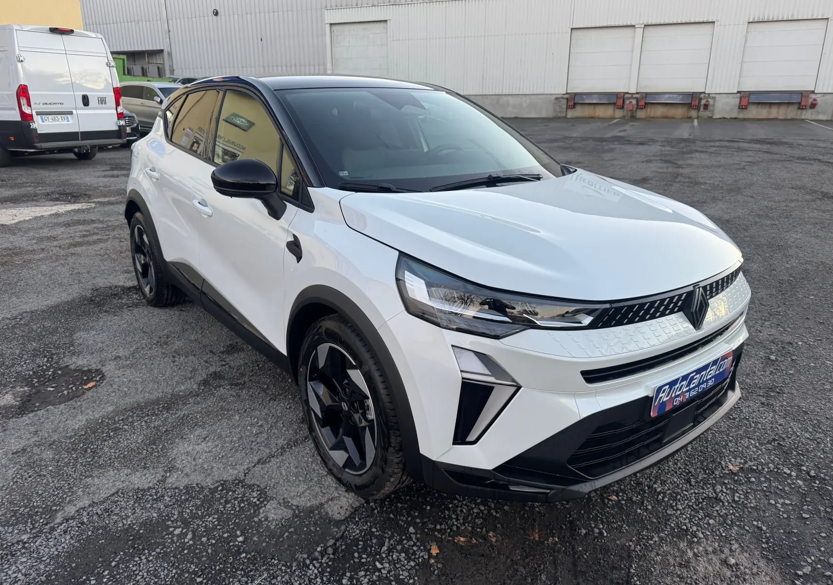 Vue 3/4 avant droite d’un Renault Captur 2025 blanc nacré avec toit noir et jantes noires sur parking.