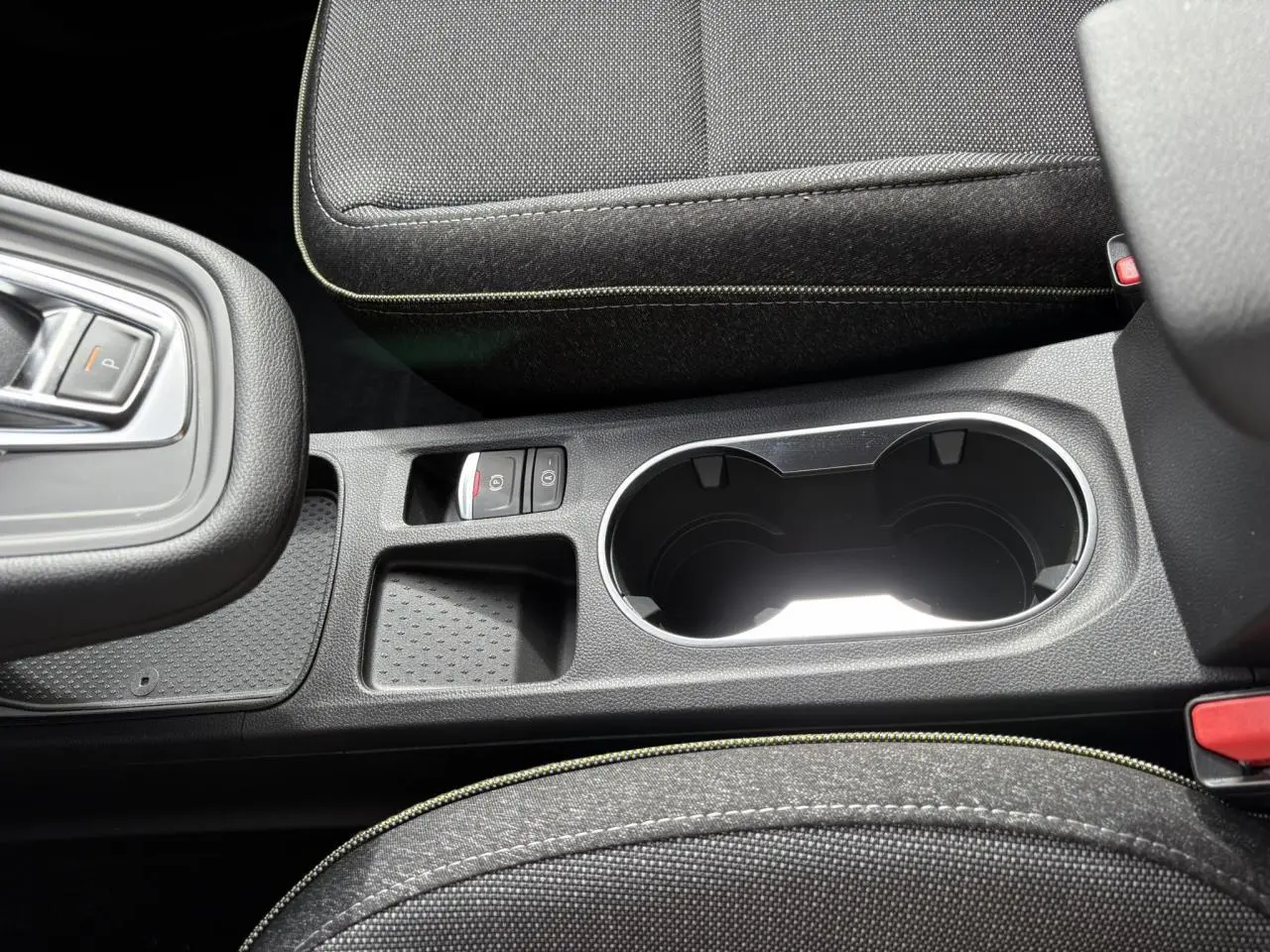 Vue rapprochée de la console centrale noire avec porte-gobelets et bouton frein de parking du Renault Symbioz gris Rafale.