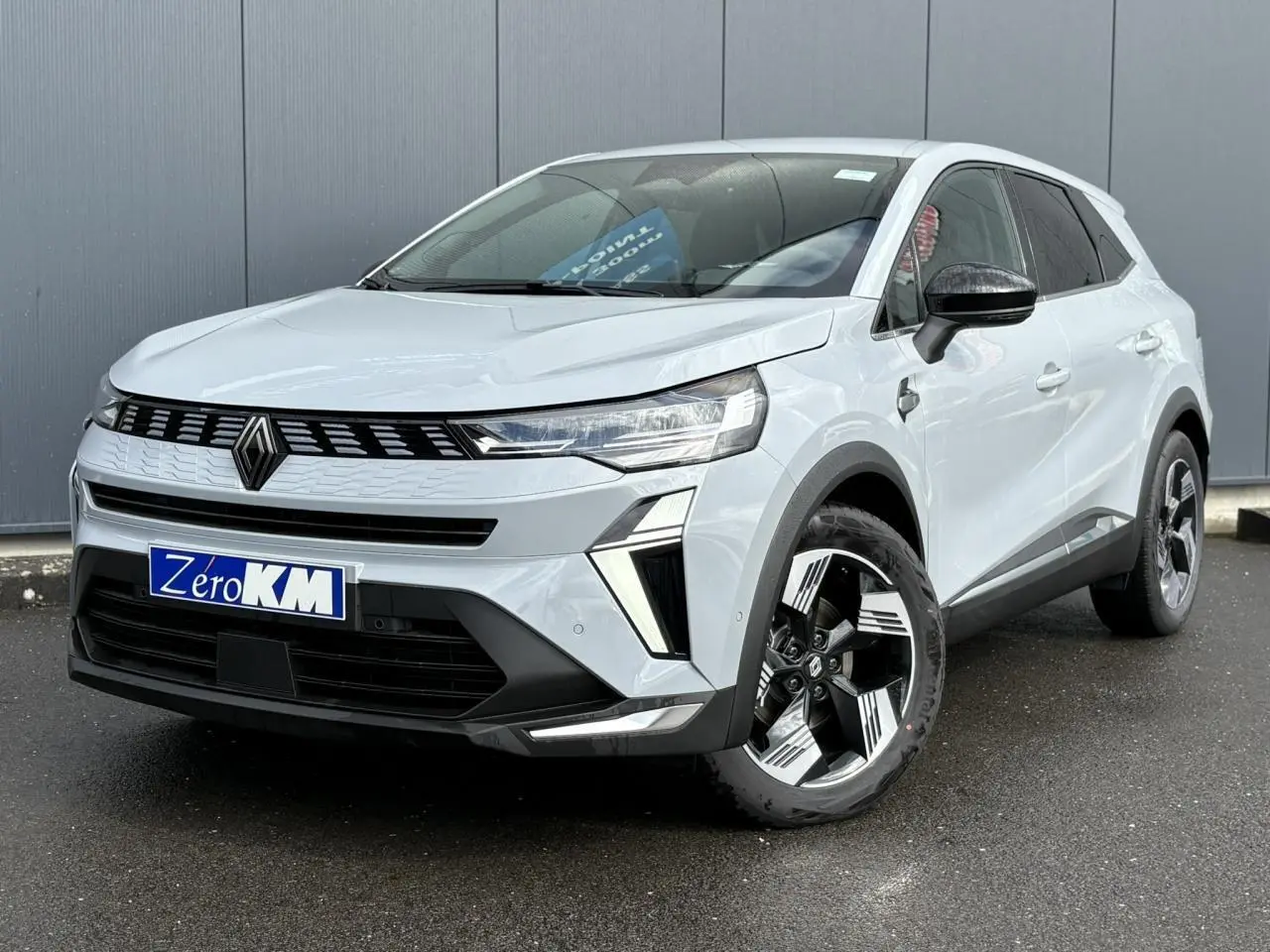 Renault Symbioz gris Rafale en 3/4 avant droit, avec jantes noires et blanches et calandre moderne noire.