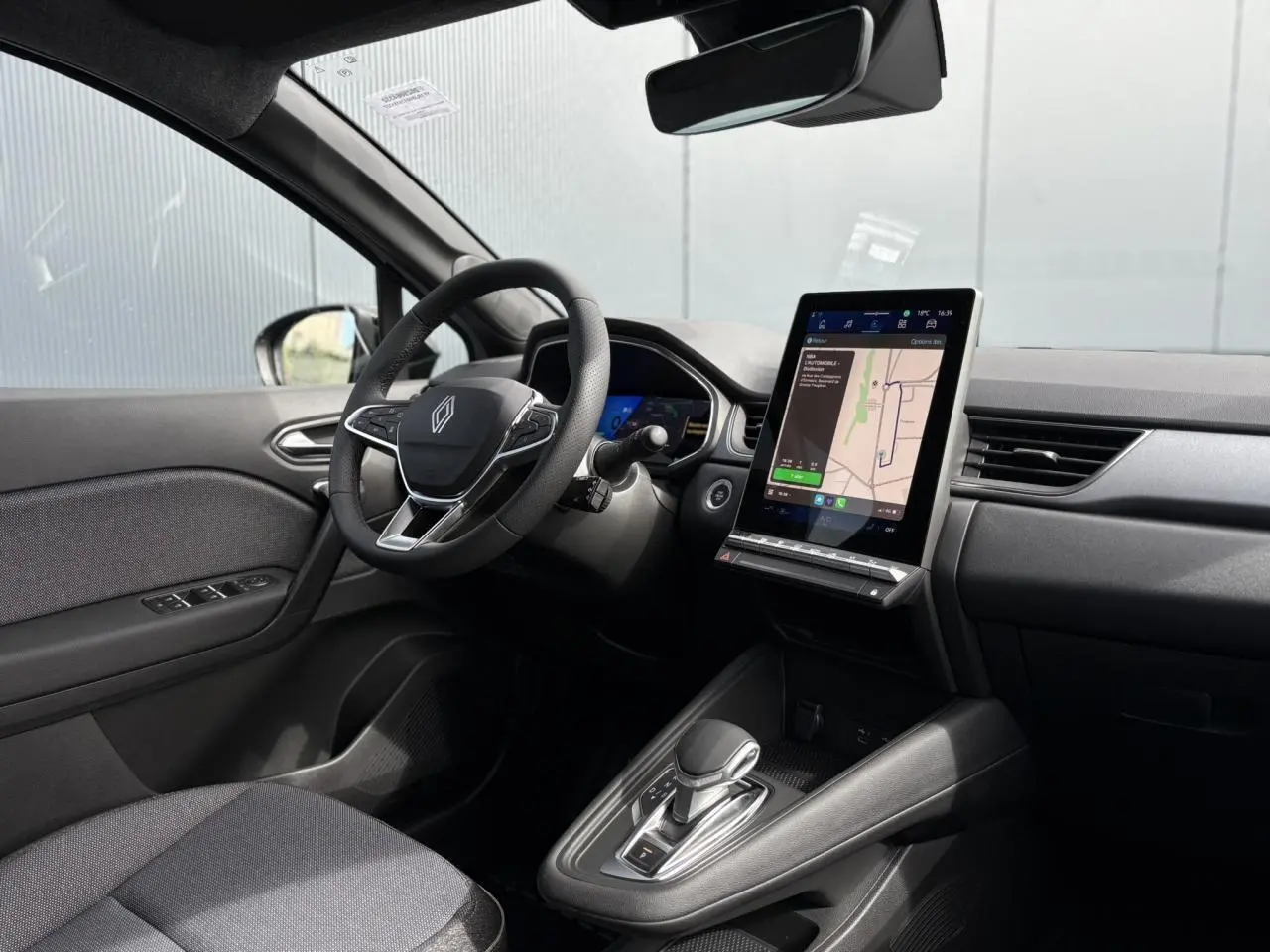 Intérieur de la Renault SYMBIOZ E-Tech 2025, vue côté conducteur, tableau de bord avec écran tactile GPS et volant cuir.