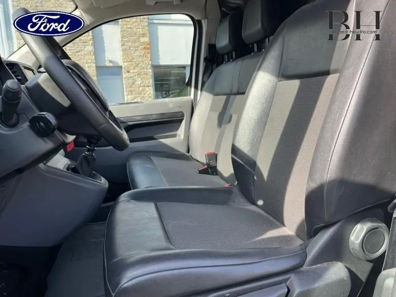 Vue intérieure côté conducteur montrant les sièges avant noirs en tissu et cuir du Peugeot Expert Fourgon blanc Banquise 2021