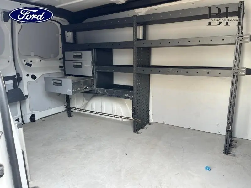 Vue intérieure arrière droite d'un fourgon blanc avec étagères métalliques noires et tiroirs intégrés.