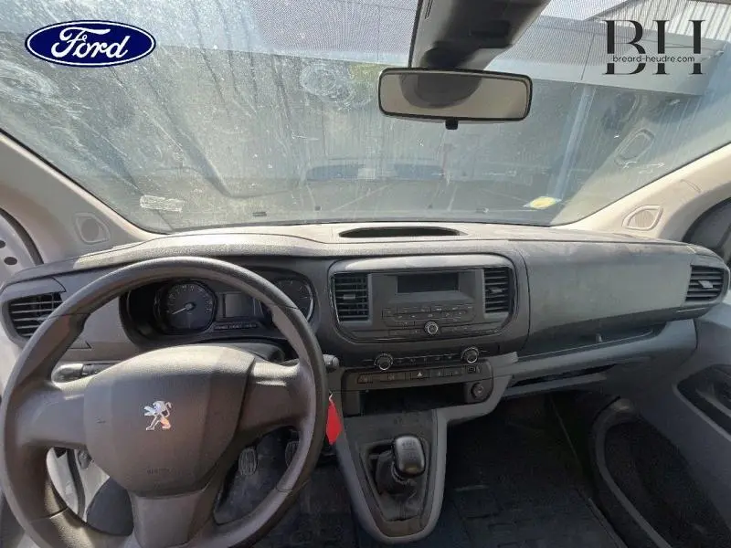 Vue intérieure avant du Peugeot Expert Fourgon blanc Banquise, tableau de bord et volant avec logo lion visibles.