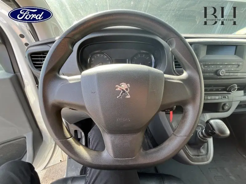 Vue centrée sur le volant noir du Peugeot Expert Fourgon blanc, avec tableau de bord et levier de vitesses manuelle visibles.