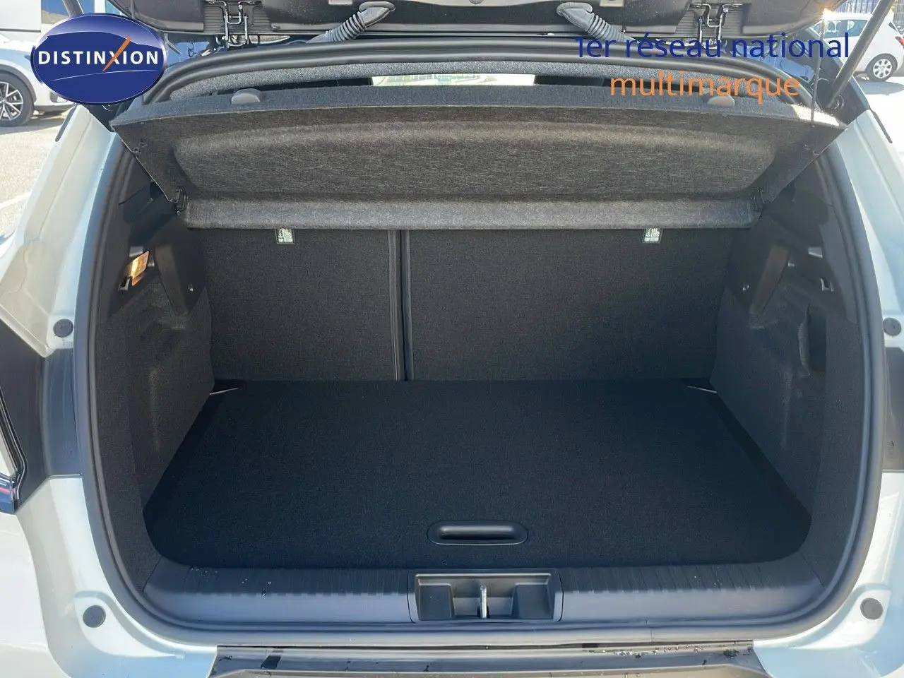 Coffre ouvert vu de l'arrière d'un Renault Captur blanc nacré avec toit noir, montrant un espace de chargement vide et propre.