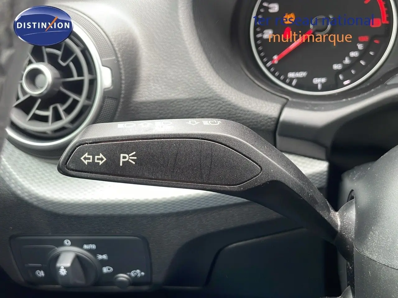 Gros plan sur la commande de clignotants à gauche du volant dans l’habitacle d’un Audi Q2 noir mito metal 2023.