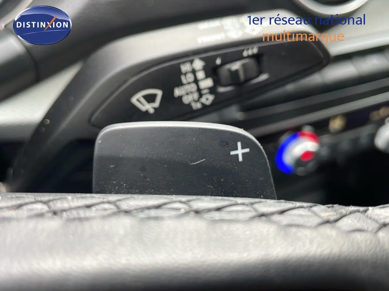 Gros plan sur la palette de changement de vitesse droite et commandes de climatisation dans l’habitacle d’un Audi Q2 noir.