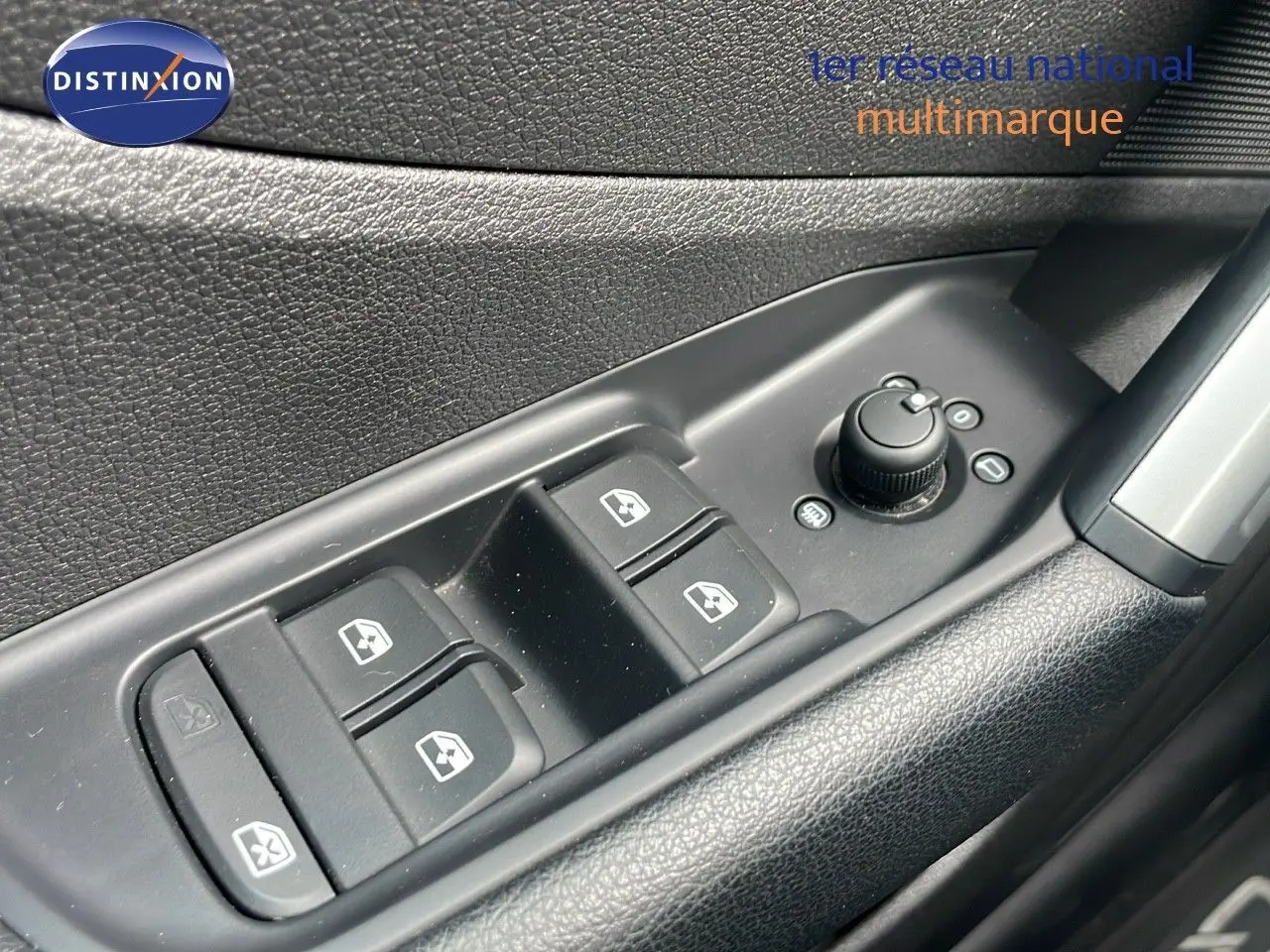 Gros plan sur les commandes de lève-vitres et réglage des rétroviseurs côté conducteur d’un Audi Q2 noir mito metal 2023.