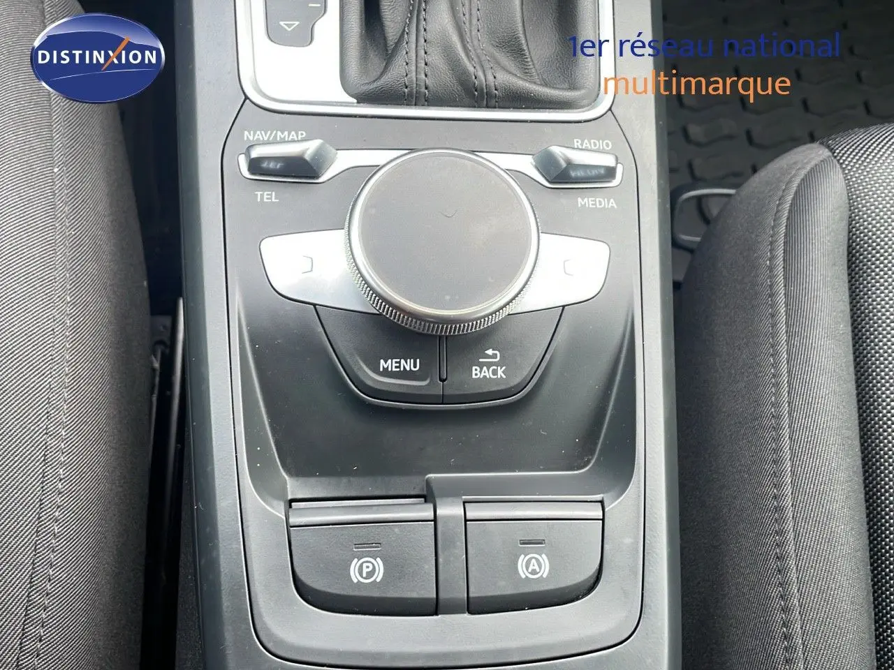 Vue rapprochée de la console centrale noire de l'Audi Q2 35 TFSI 2023, avec commandes multimédia et frein électronique.
