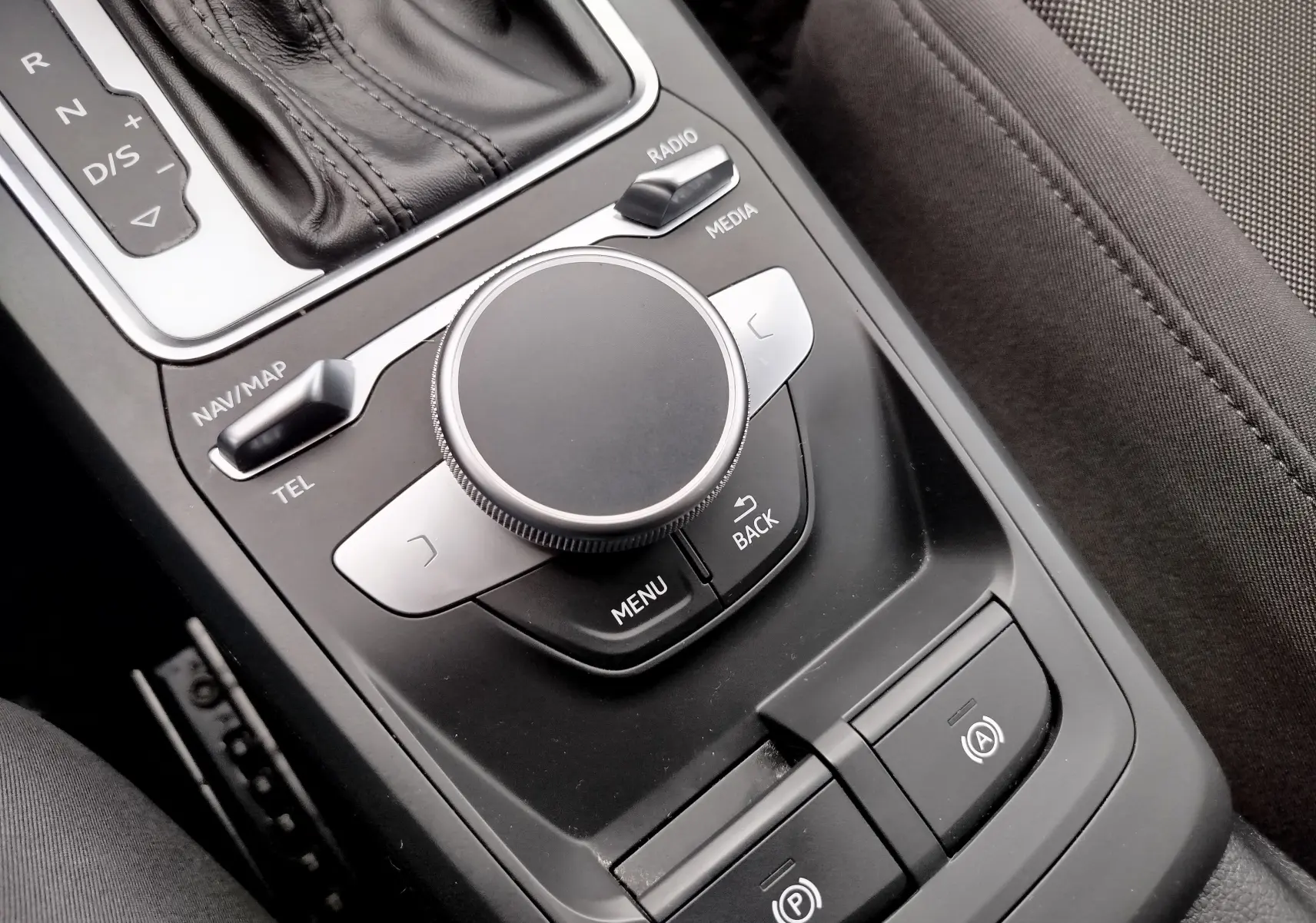 Vue rapprochée de la molette de commande multimédia et levier de vitesse cuir noir dans l'Audi Q2 35 TFSI S-Line 2023.