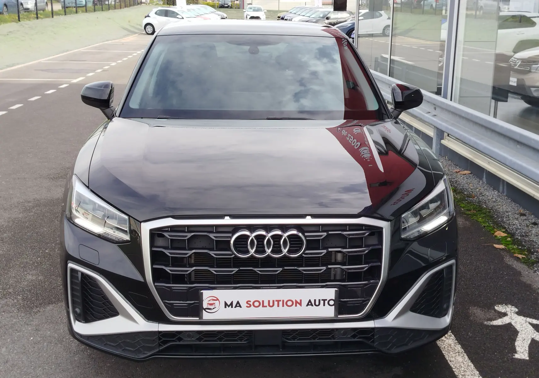 Audi Q2 noir mito metal en vue 3/4 arrière droit, mettant en valeur ses feux arrière et ses jantes argentées.