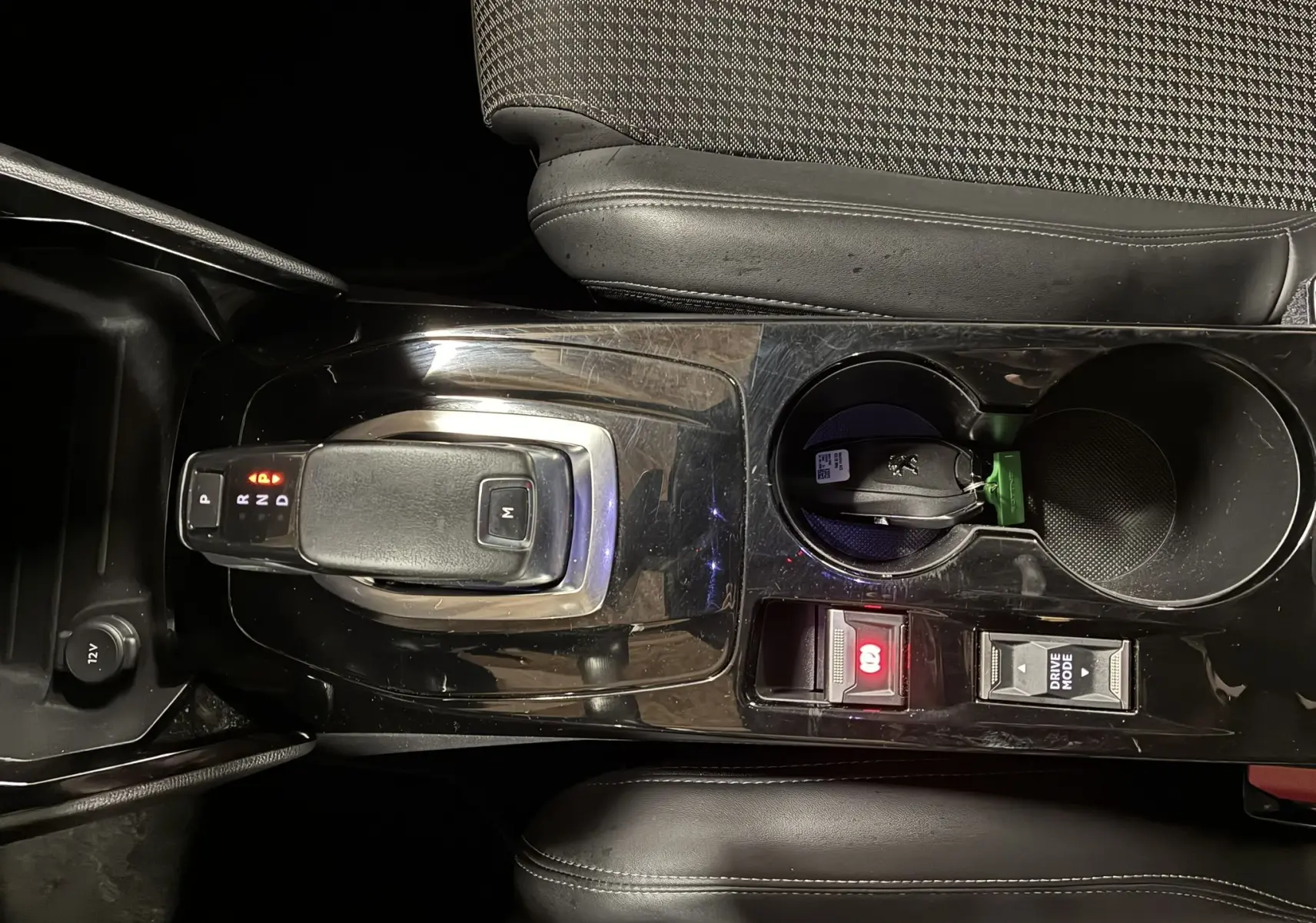 Vue rapprochée de la console centrale noire du Peugeot 2008 1.5 BlueHDi 130 GT Line avec levier de vitesse automatique et clé dans porte-gobelet.