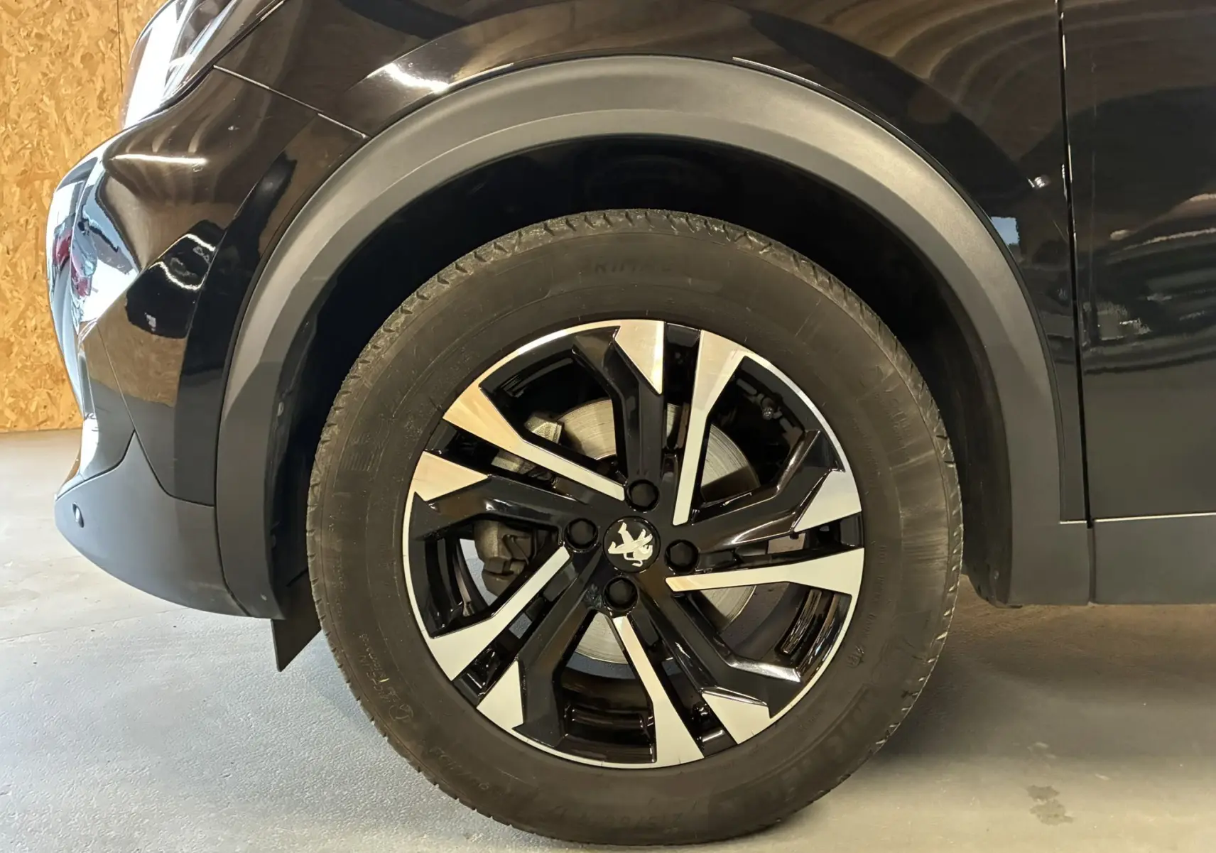 Gros plan sur la roue avant gauche noire d'un Peugeot 2008 GT Line 2020 avec jante bi-ton distinctive.