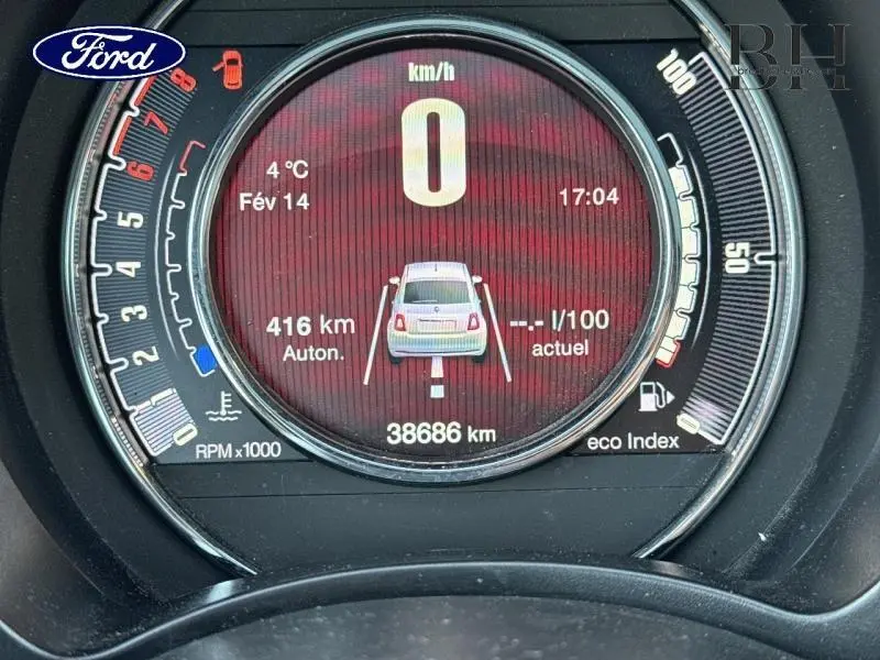 Vue rapprochée du tableau de bord numérique de la Fiat 500 avec affichage rouge et indicateurs blancs.