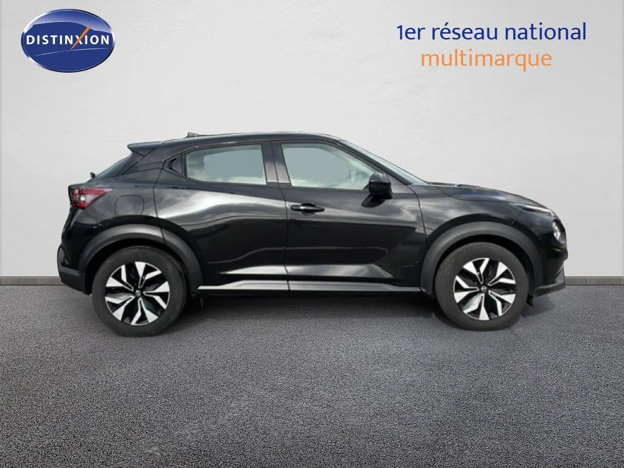 Vue de profil côté gauche d'un Nissan Juke noir perle métal 2023 avec jantes bicolores et lignes dynamiques.