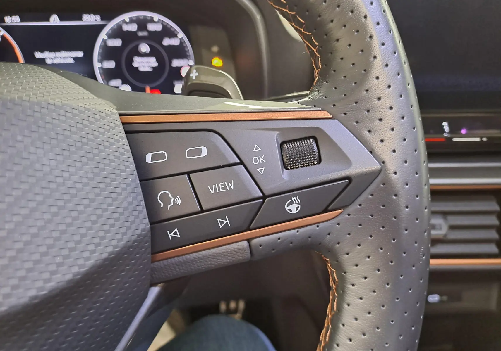 Gros plan sur les commandes du volant en cuir noir perforé avec surpiqûres copper du CUPRA Formentor 2023.