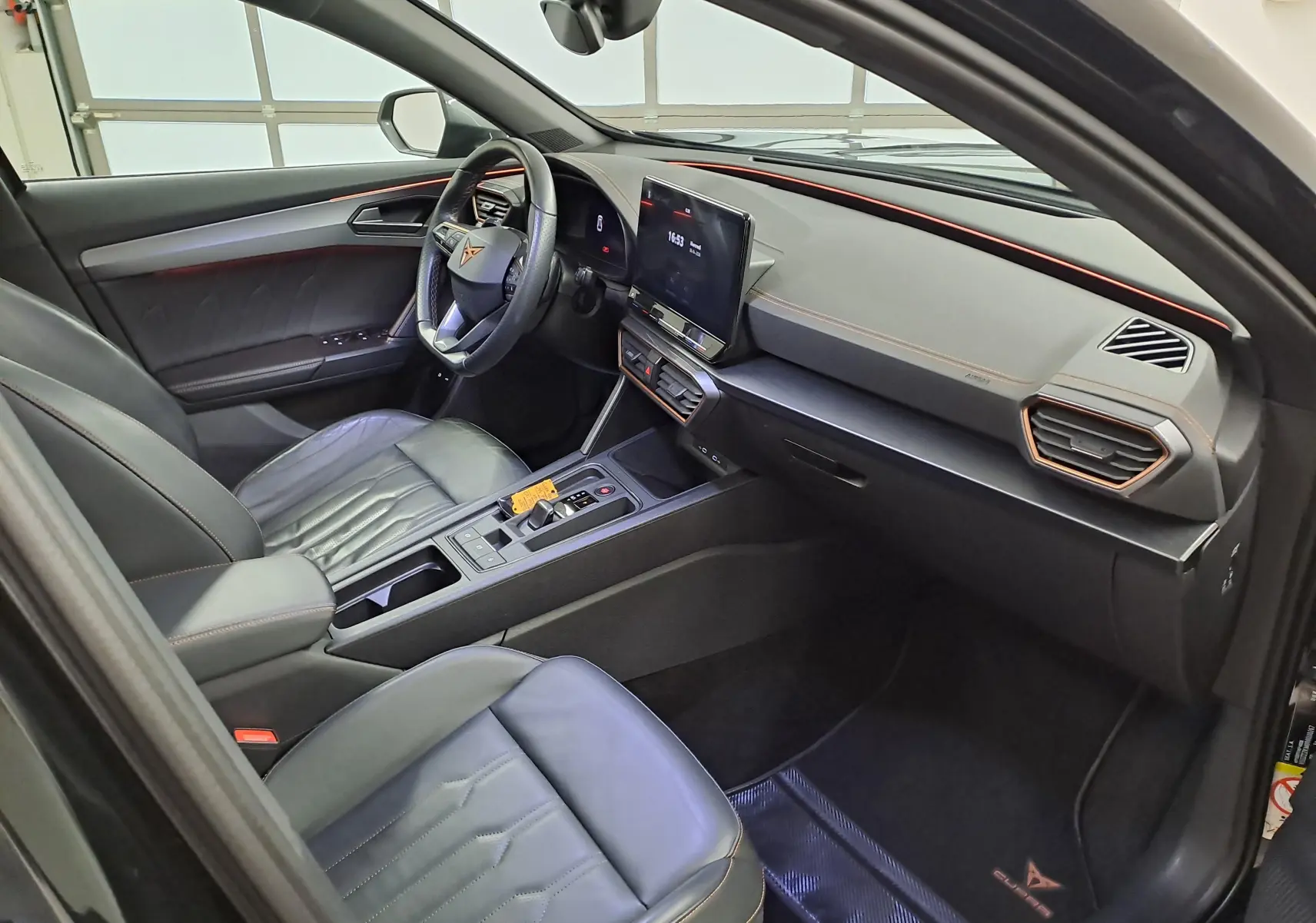 Vue intérieure côté conducteur du CUPRA Formentor 1.4 e-HYBRID 2023 avec cuir noir, surpiqûres cuivre et tableau de bord moderne.