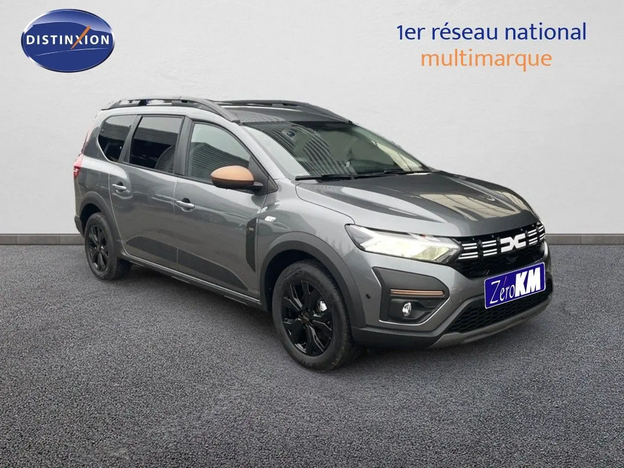 Dacia Jogger gris schiste métal en 3/4 avant droit, avec jantes noires et rétroviseurs couleur beige.
