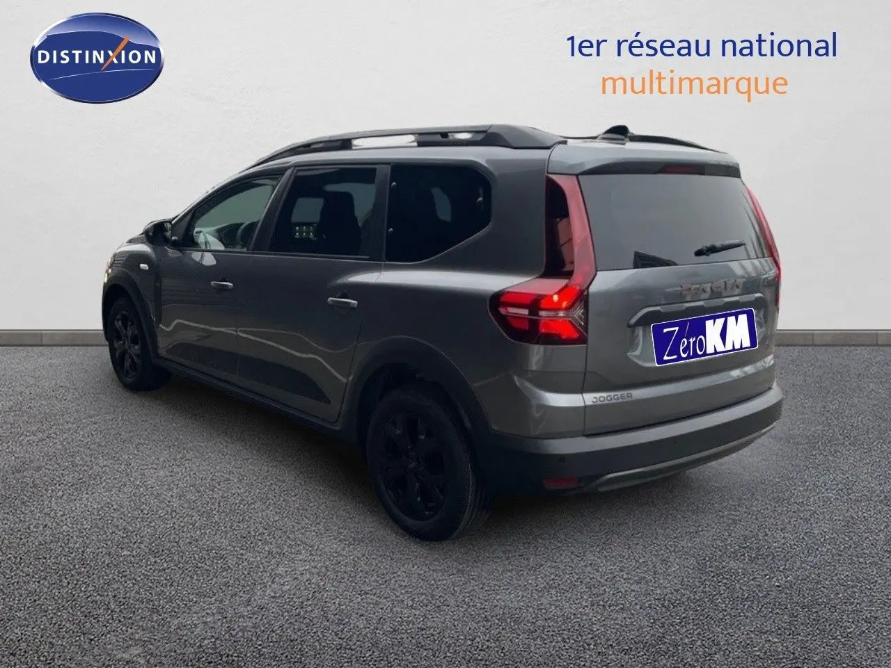 Vue 3/4 arrière droite d'un Dacia Jogger gris schiste métallisé avec feux arrière allumés sur fond neutre.