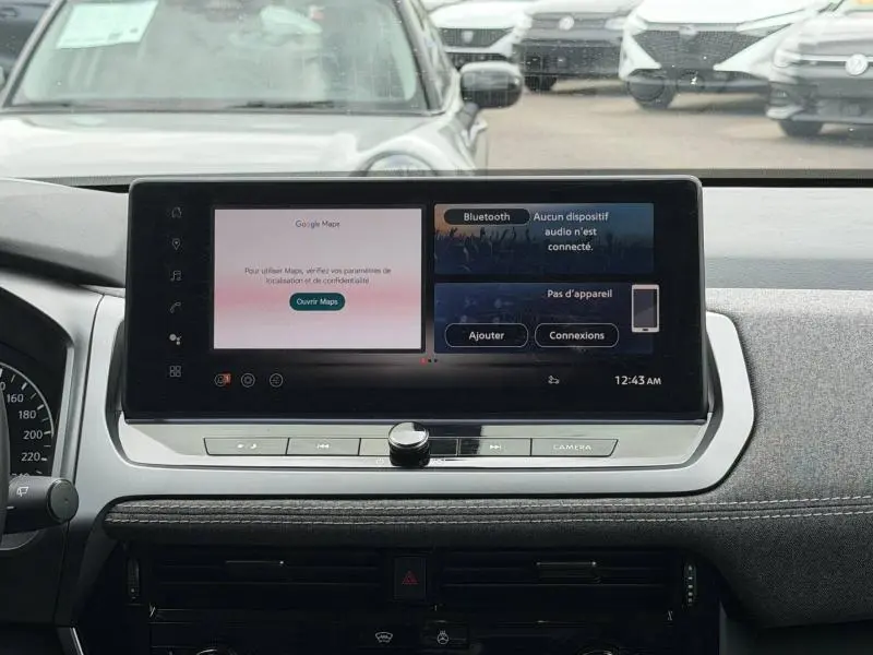 Vue frontale de l'écran tactile central du tableau de bord du Nissan Qashqai blanc nacré 2025 avec interface multimédia affichée.