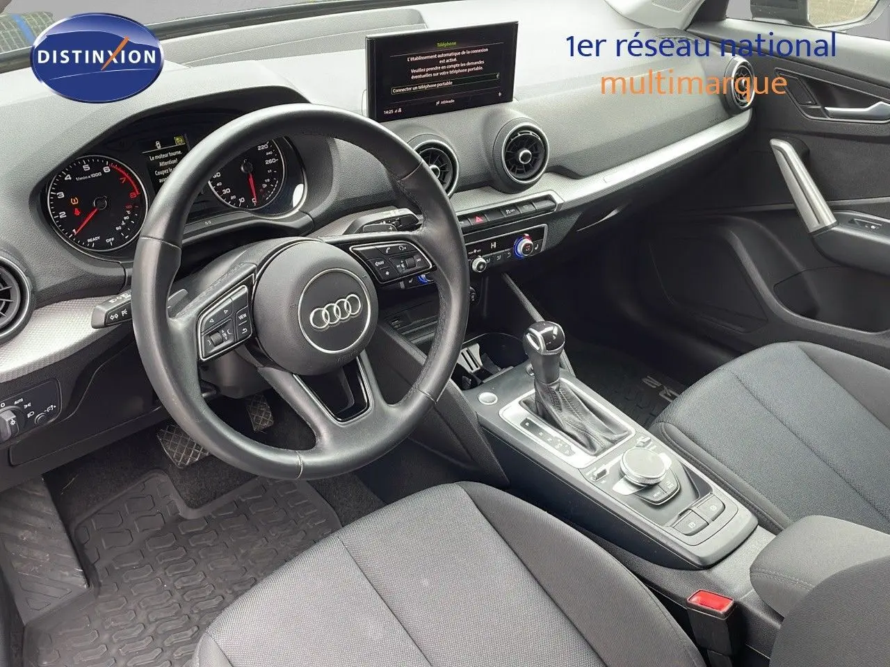 Intérieur de l'Audi Q2 35 TFSI S-Line 2023 vu côté conducteur, avec volant multifonction et console centrale moderne.