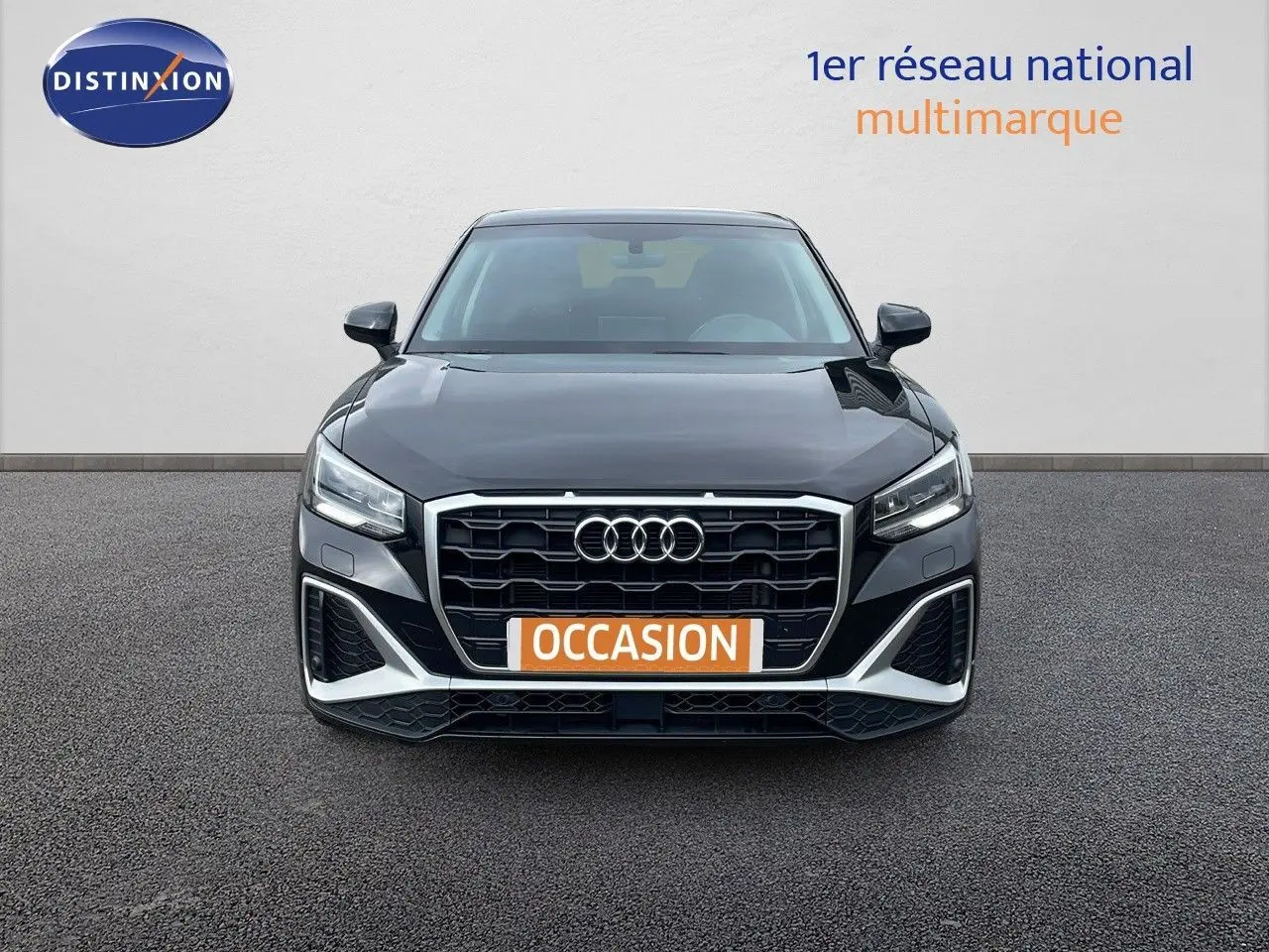 Vue frontale d'un Audi Q2 35 TFSI S-Line noir mito metal avec calandre hexagonale et phares LED allumés.
