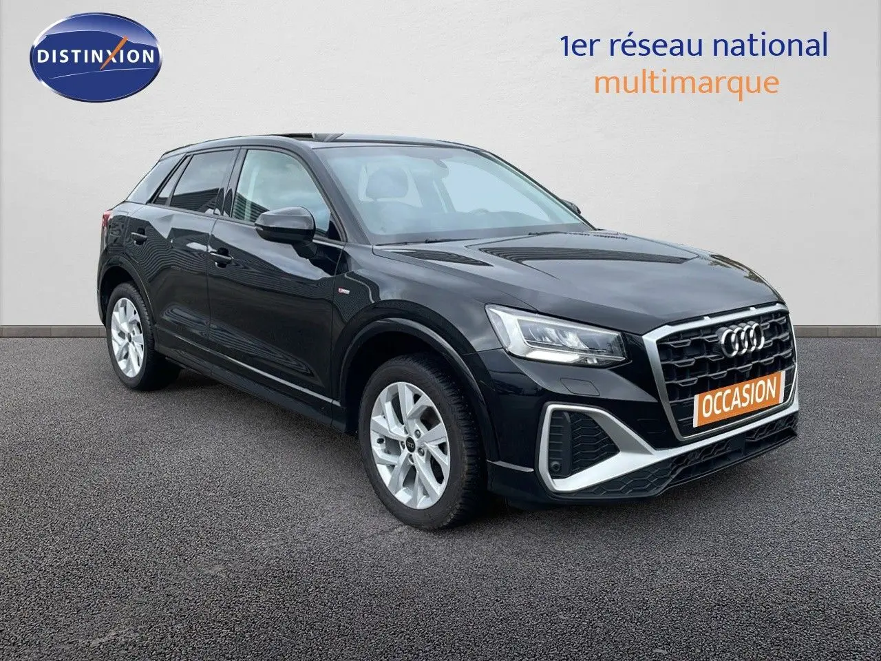 Audi Q2 noir mito metal en 3/4 avant droit, avec calandre S-Line et jantes argentées visibles sur sol gris.