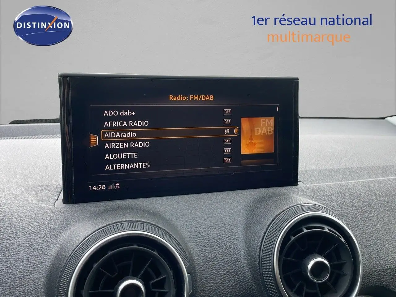 Écran central tactile affichant les stations radio FM/DAB dans l'habitacle d'un Audi Q2 noir mito metal.