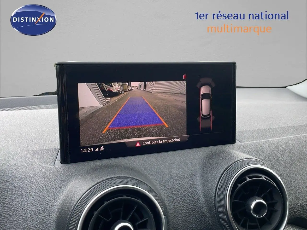 Écran multimédia affichant la caméra de recul et l'aide au stationnement d'un Audi Q2 noir mito metal, intérieur moderne.