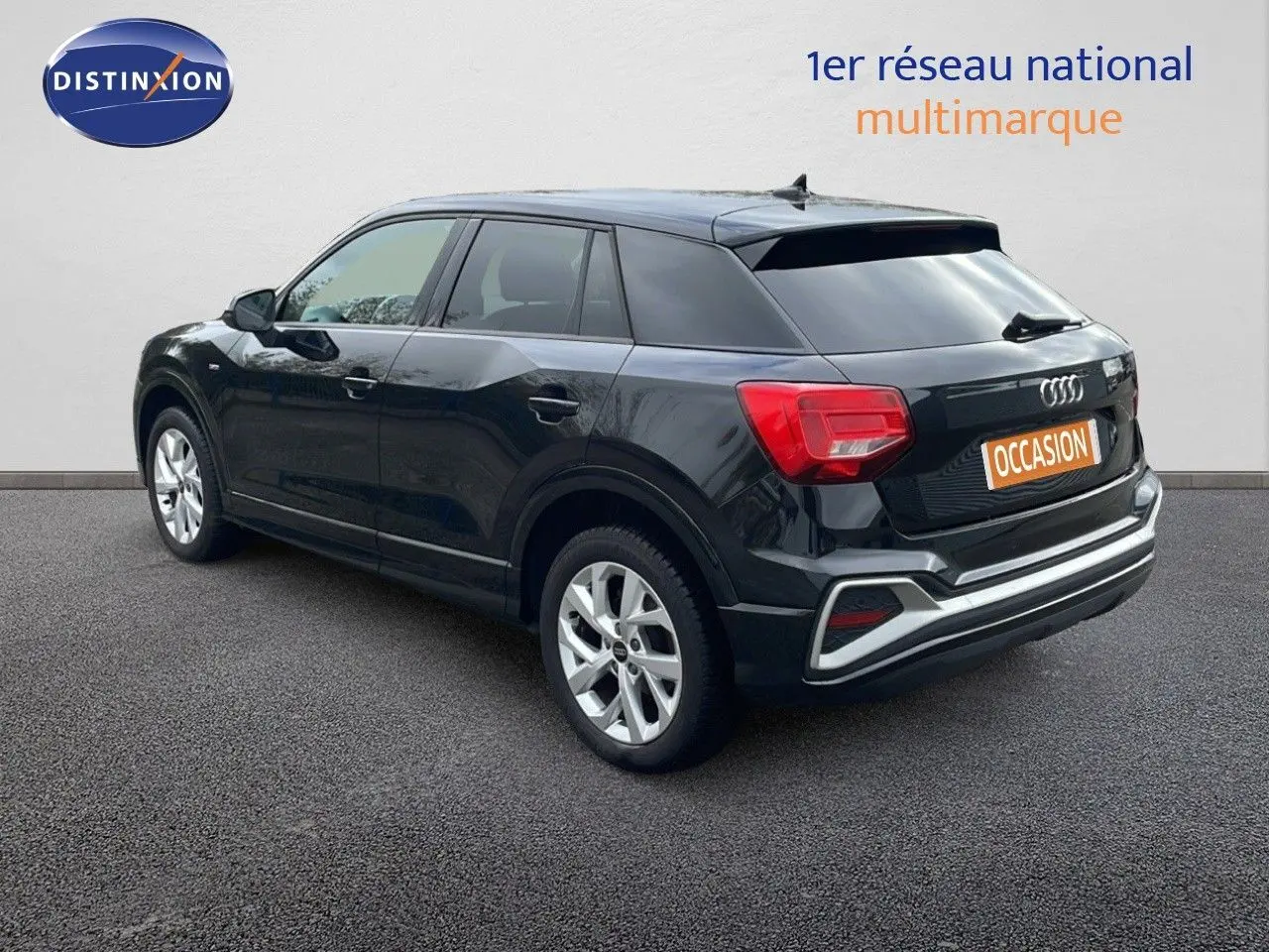 Audi Q2 noir mito metal vue 3/4 arrière côté gauche, avec feux arrière rouges et jantes argentées.