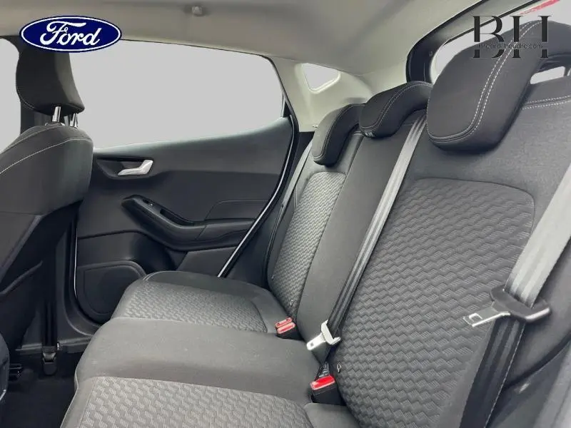 Vue intérieure côté droit montrant la banquette arrière en tissu noir avec appuie-têtes et ceintures de sécurité.