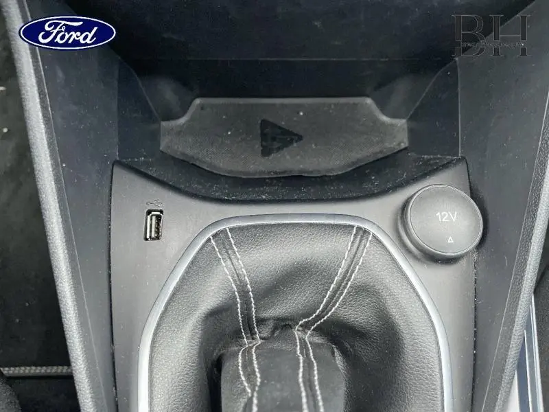 Gros plan sur la console centrale noire de la Ford Fiesta 2022, montrant le soufflet de levier de vitesses et prise 12V.