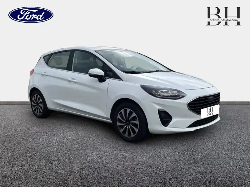 Ford Fiesta blanc glacier vue 3/4 avant droit avec calandre noire et jantes alu distinctives.