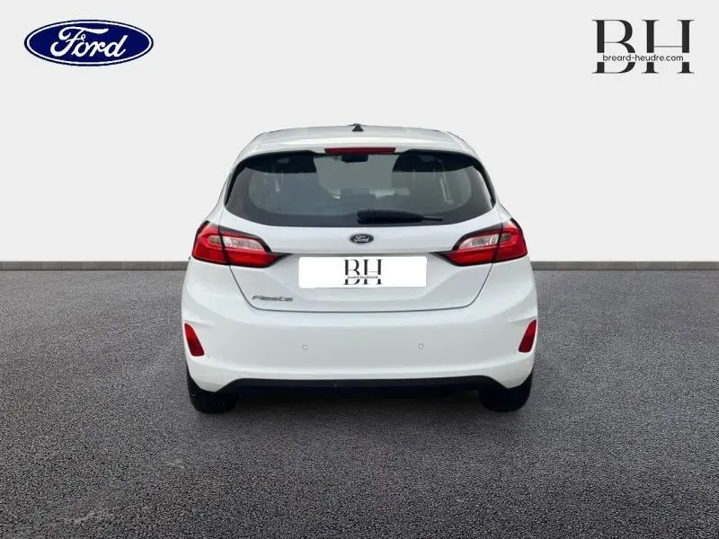 Vue arrière d'une Ford Fiesta blanche Glacier 2022 avec feux arrière rouges et hayon fermé sur fond neutre.