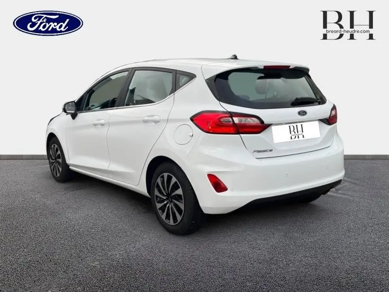 Vue 3/4 arrière droite d'une Ford Fiesta blanc glacier avec jantes alu et becquet arrière.