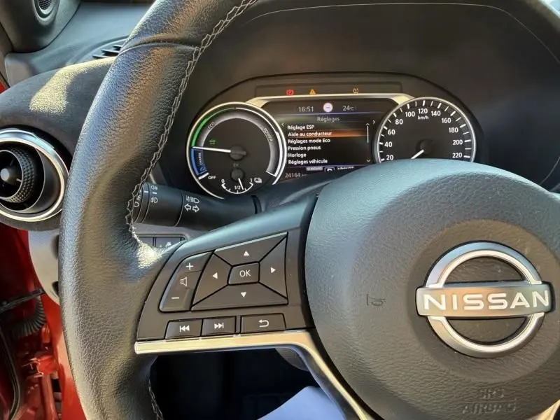 Vue rapprochée du volant en cuir noir du Nissan Juke 2024 avec tableau de bord numérique et détails des commandes intégrées.